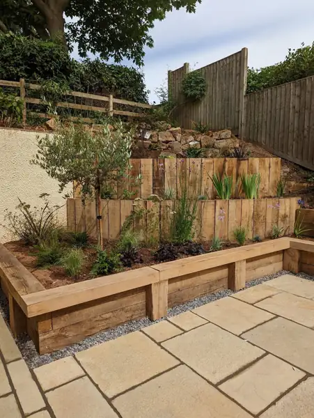 Sandstone patio framed by oak sleeper planters