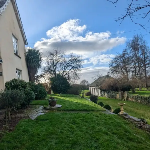 Sloping country garden with mown lawn and mature trees